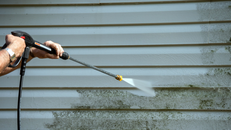 An,Unidentified,Man,Uses,A,Power,Washer,To,Clean,Mold